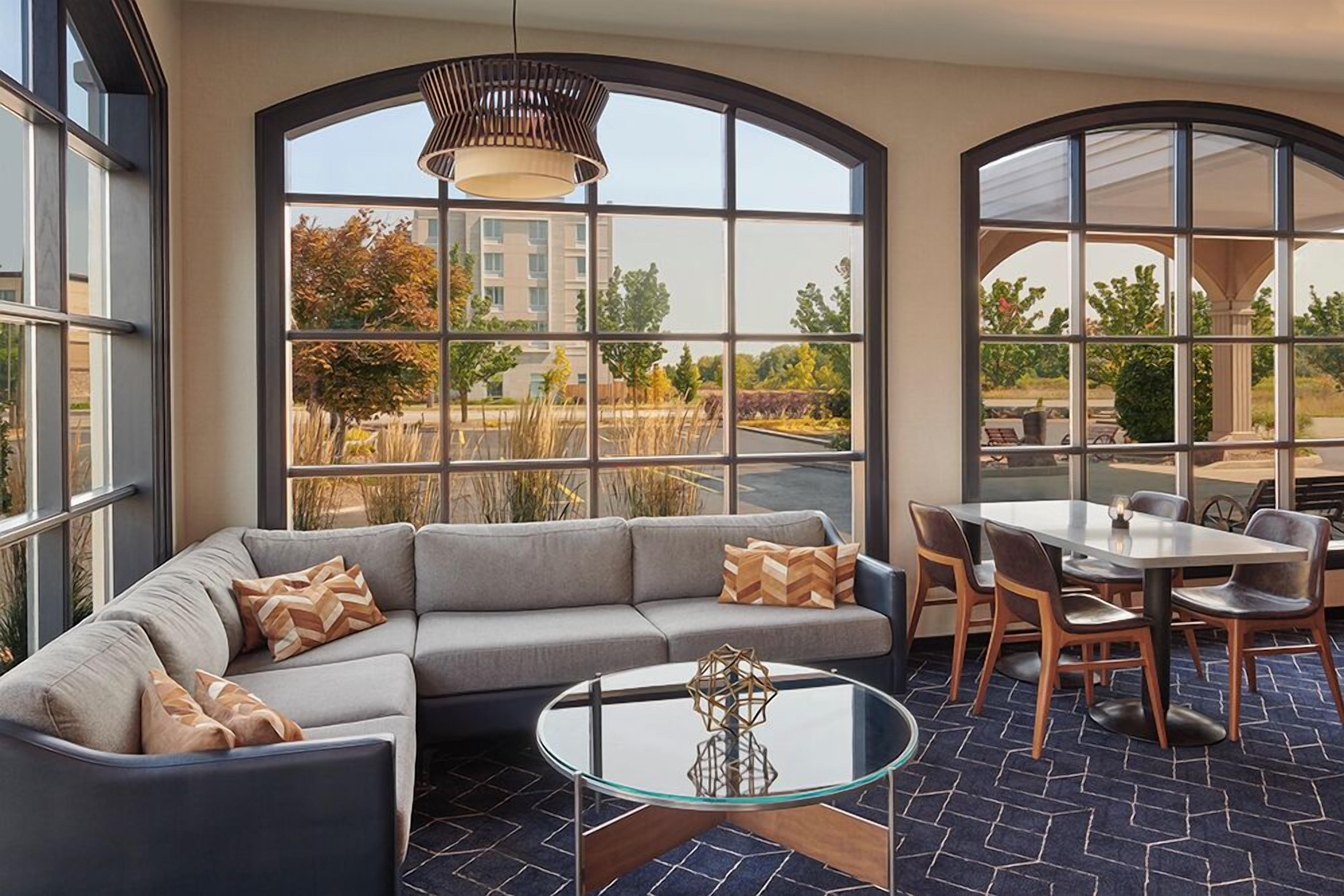 A modern lounge area with a curved sofa, a glass coffee table, and a dining set.