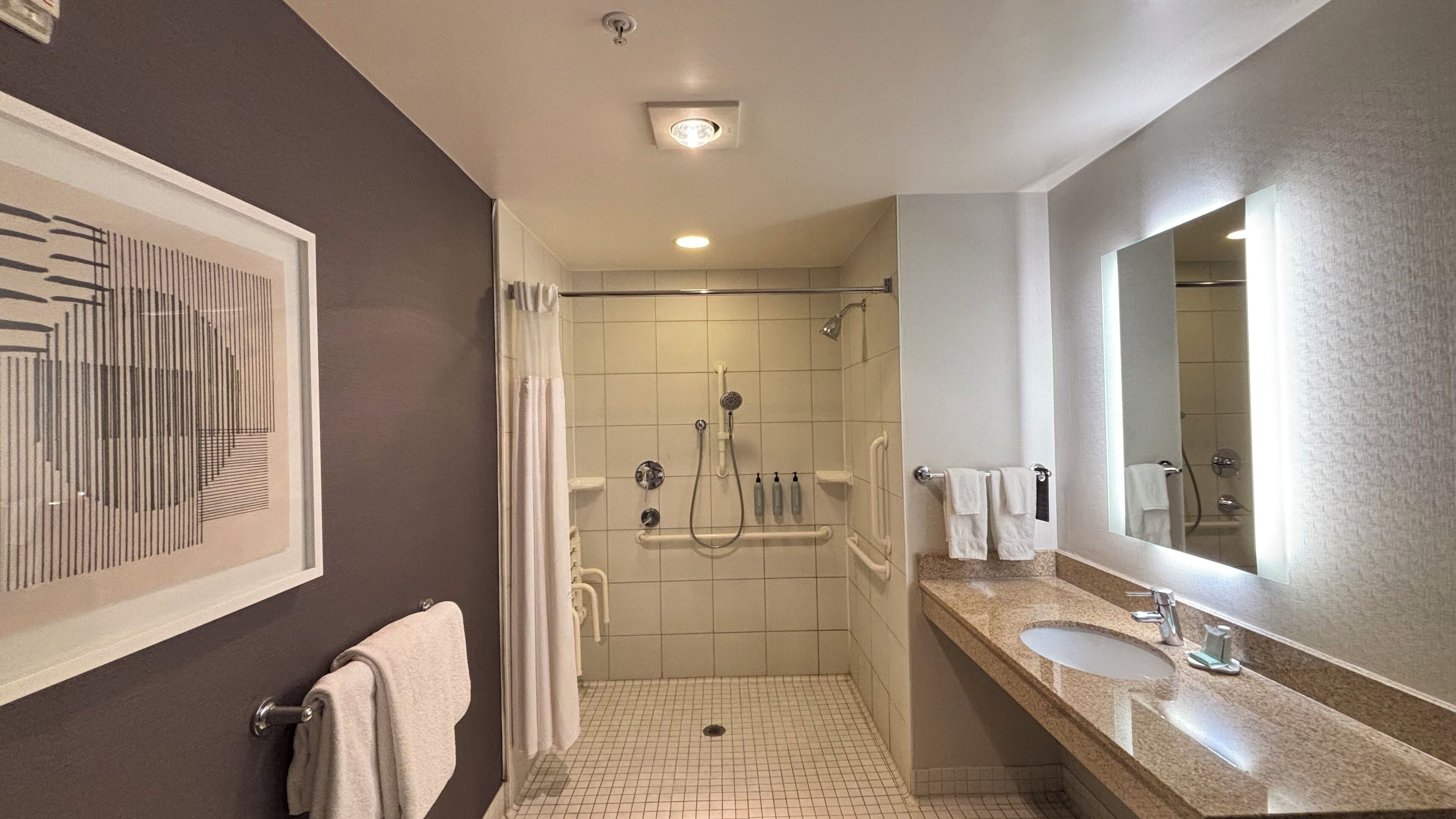 A modern bathroom with a shower, sink, and a large mirror.