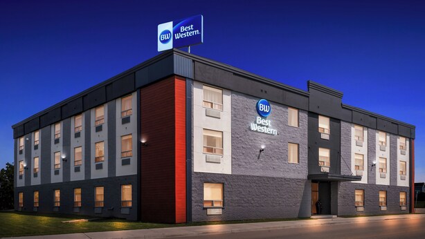 A Best Western hotel with a modern design, featuring a prominent sign, multiple windows, and a well-lit facade. - Best Western Swan Castle Inn (Cochrane)