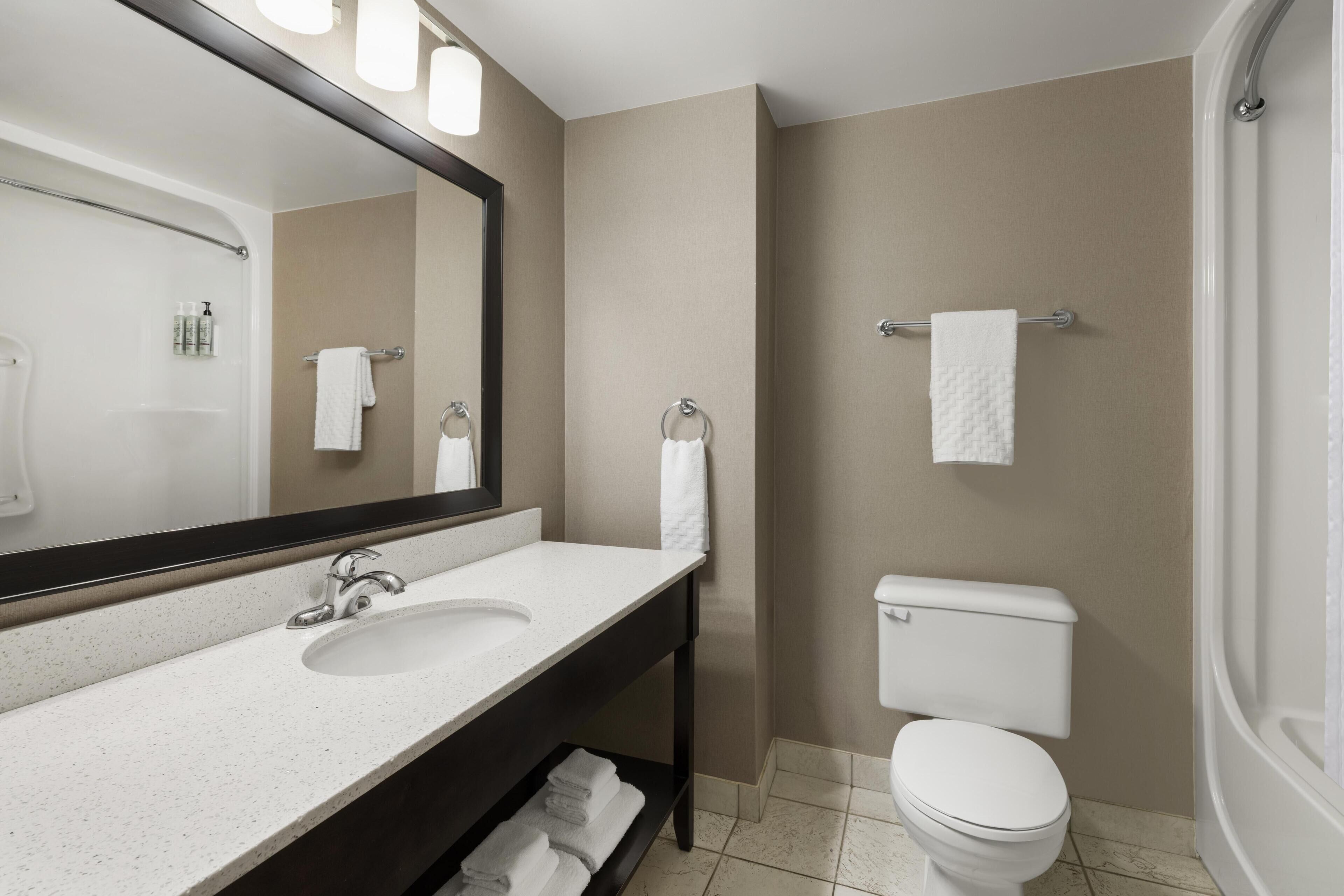 A bathroom with a white sink, a mirror, a toilet, and a towel rack.