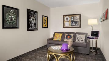 A living room with a grey sofa, a round coffee table, and framed pictures on the wall.
