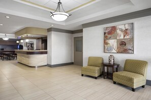 A hotel lobby with a reception desk, seating area, and a kitchen in the background. - Best Western Swan Castle Inn (Cochrane)
