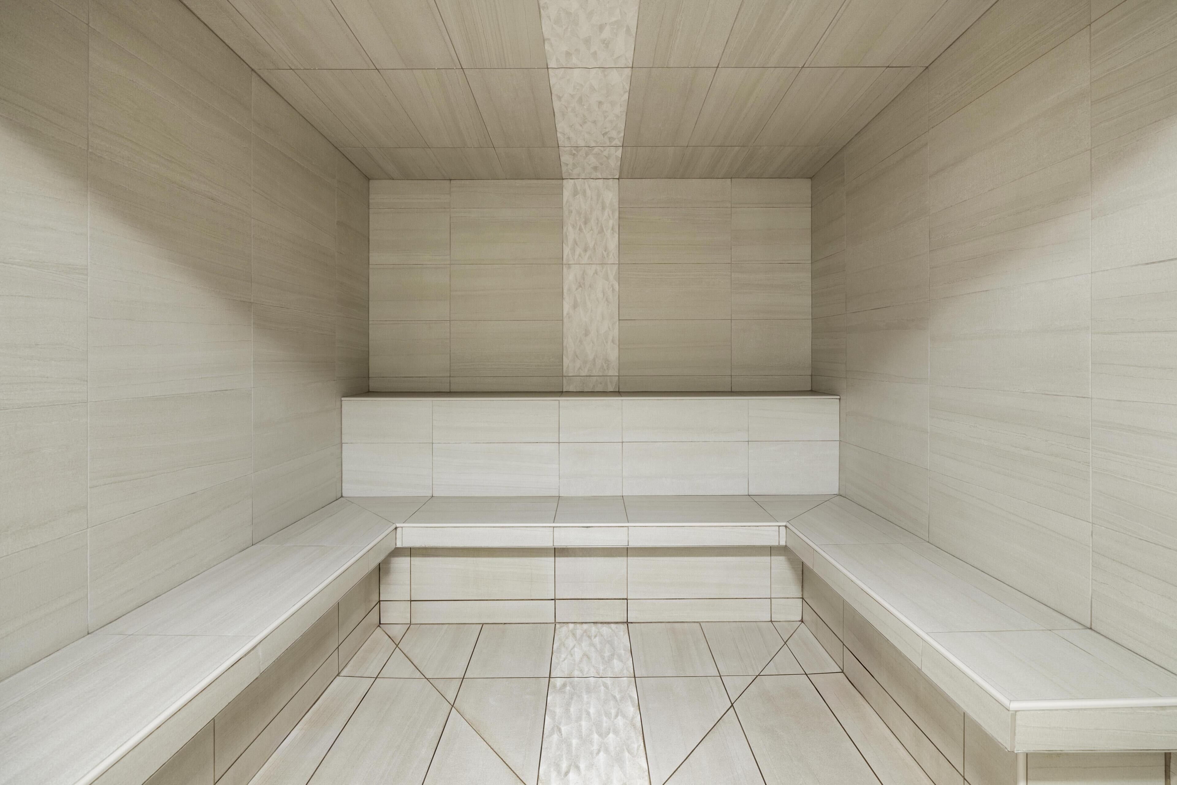 A modern, empty room with a bench and tiled walls.