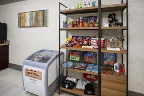 Uma máquina de vendas identificada como 'Swan Bistro' com snacks e uma prateleira com diversos itens, incluindo snacks, livros e uma pequena estatueta.