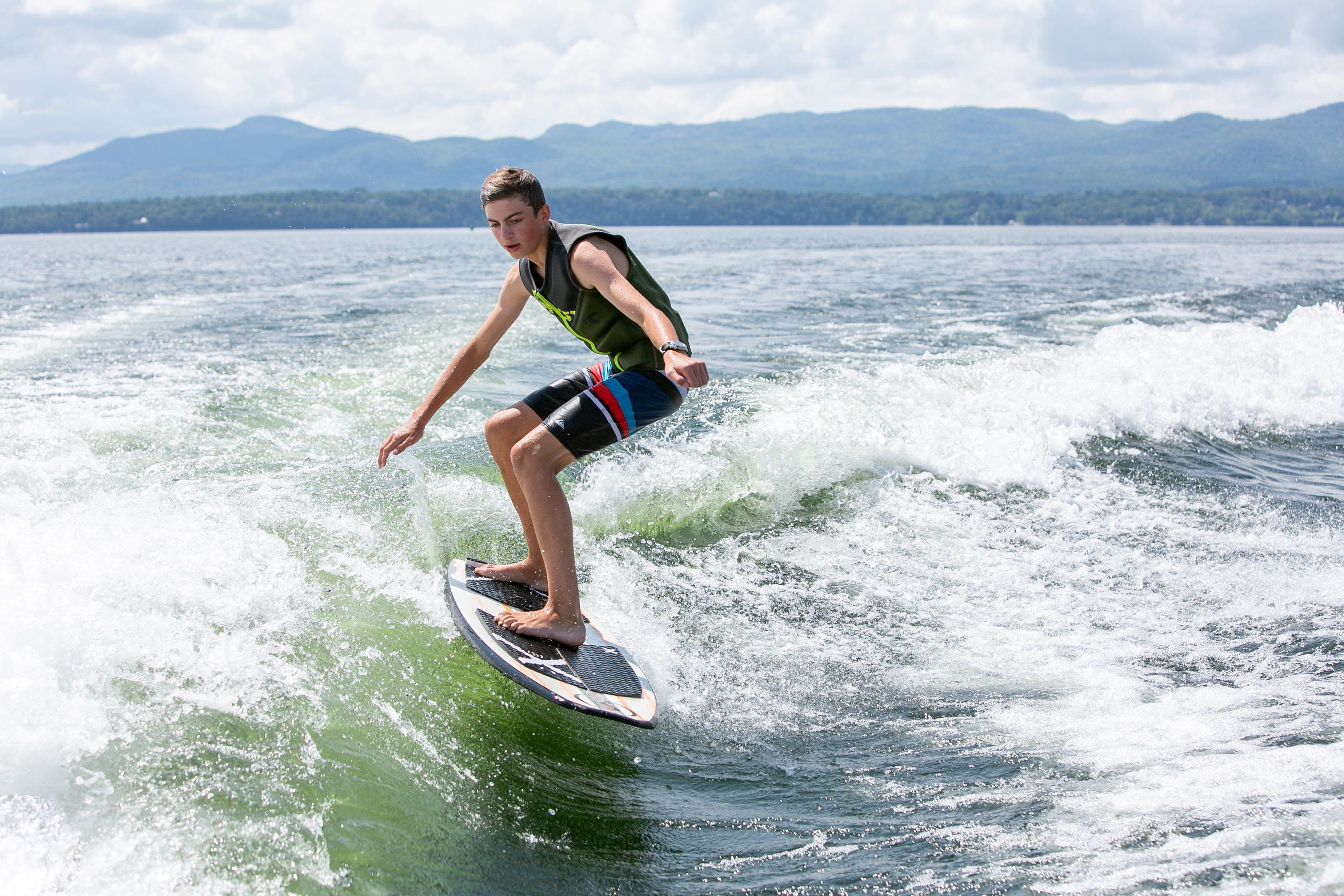 A person wakeboarding on a lake with mountains in the background.