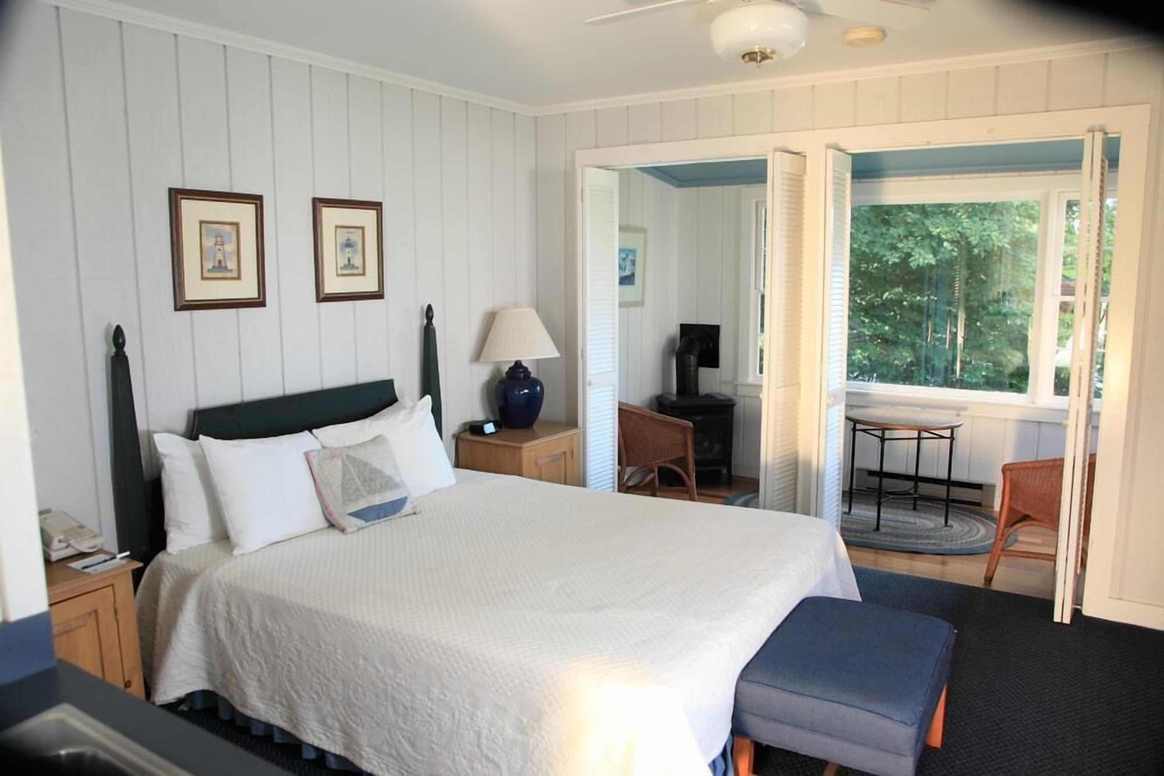 A bedroom with a large bed, a desk, a chair, and a view of the outdoors.
