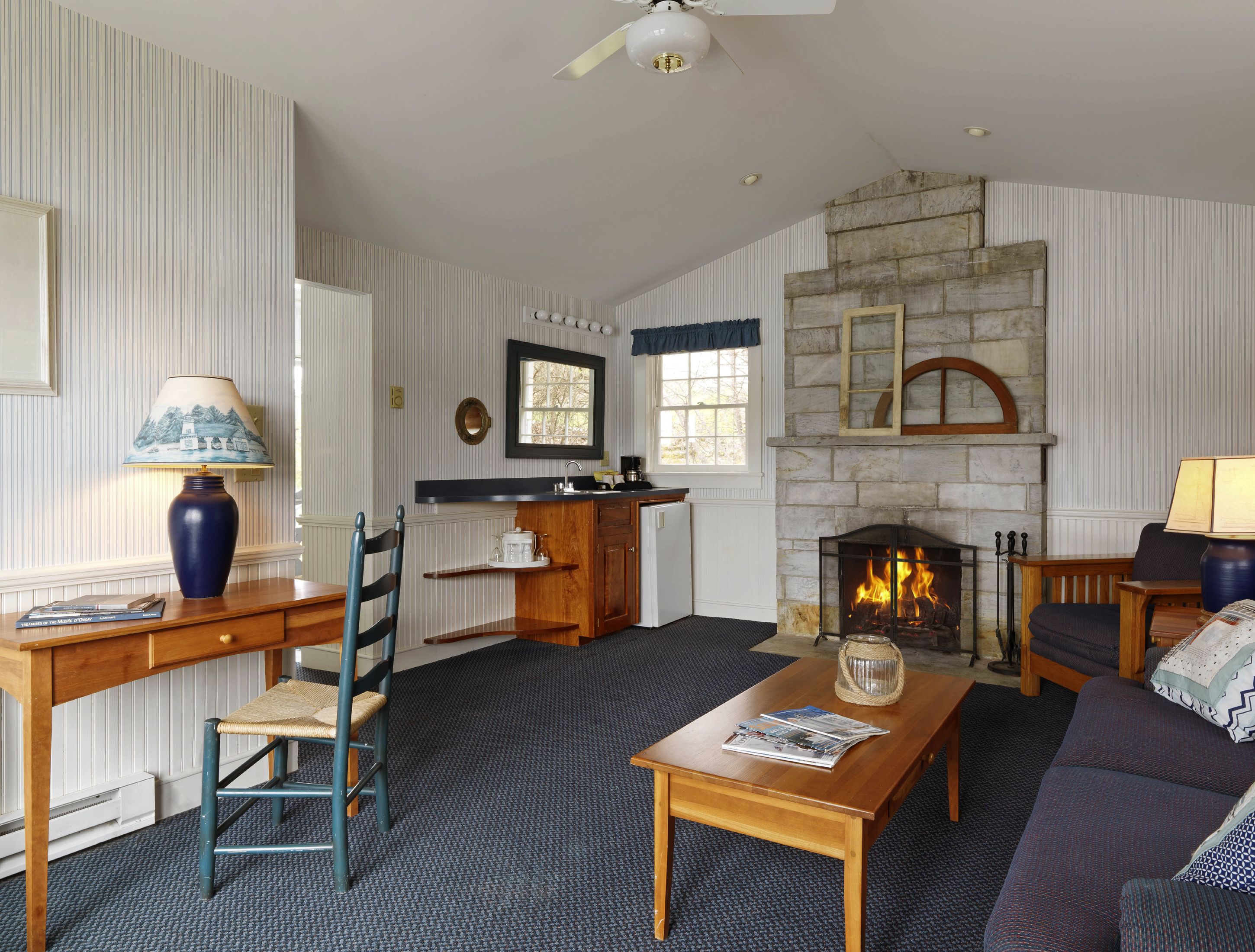 Una sala de estar con chimenea, un comedor con mesa y sillas de madera, y una cocina con mostrador y pileta.
