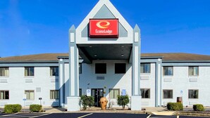 Entrada de un hotel con un letrero rojo que dice "EconoLodge". Hay espacios de estacionamiento para discapacitados y una jardinera grande al frente.
