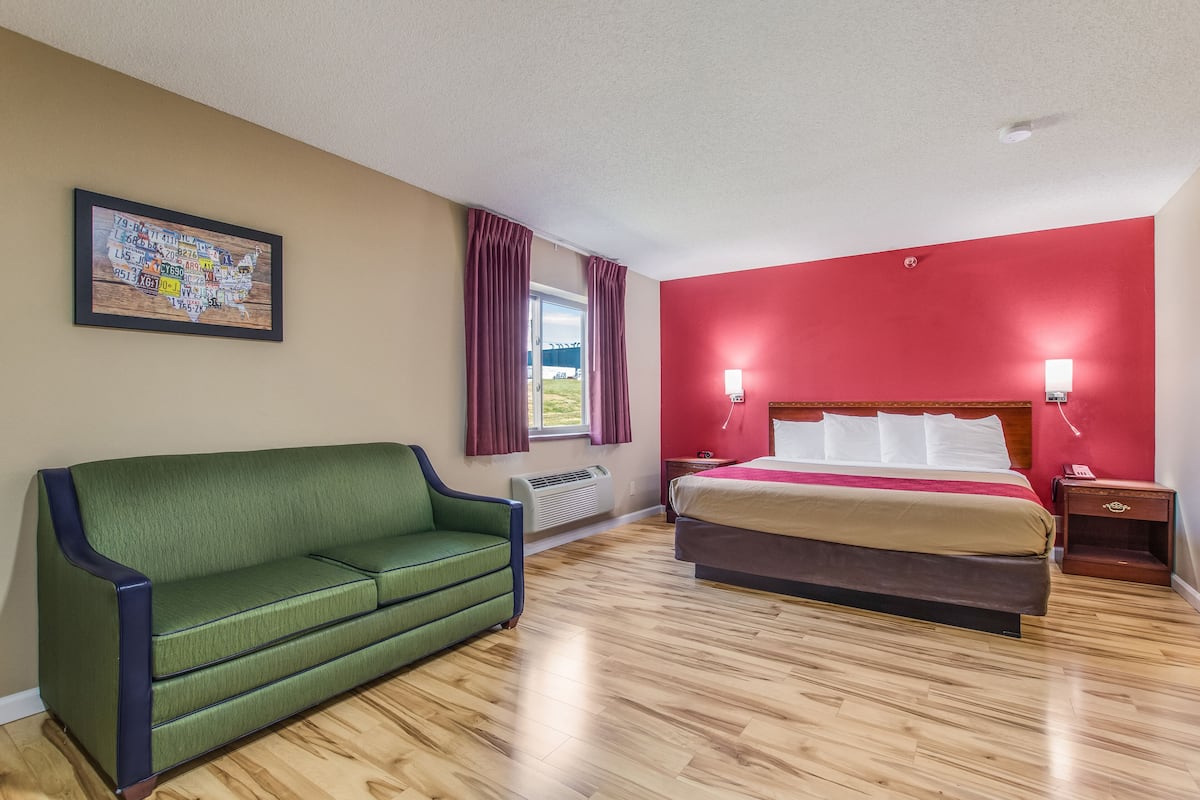 Een hotelkamer met een groene bank, een bed met een rode accentmuur en een kaart aan de muur.