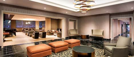 A spacious lobby with a high ceiling, a modern chandelier, and a variety of seating options including sofas and armchairs.