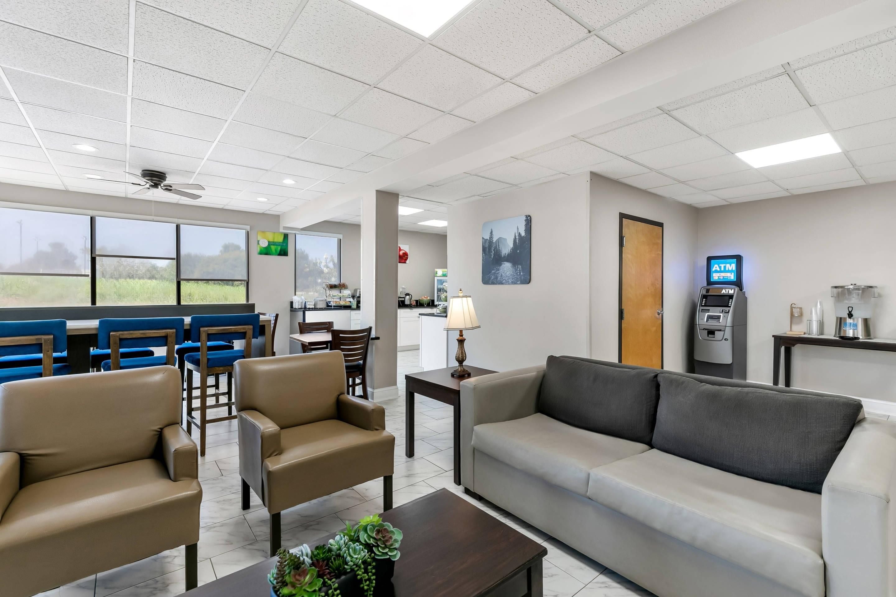 A hotel lobby with seating, an ATM, and a view of the outdoors.