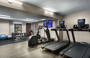 Uma academia com esteiras, elípticos e bolas de exercício.
