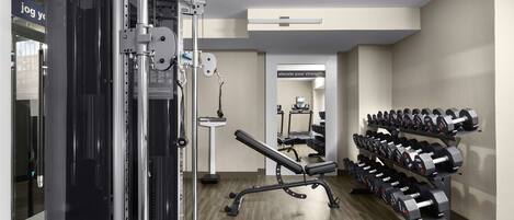 Ein Fitnessraum mit Krafttrainingsgeräten, einer Bank und einer Hantelbank.
