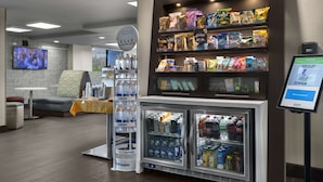 En udstilling med snacks og forarbejdede fødevarer, et køleskab fyldt med drikkevarer, og en digital informationsskærm.