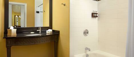 A bathroom with a black and white checkered floor, a black vanity with a mirror, a white bathtub, and a shower with a rain showerhead.