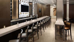 A modern bar area with a long counter, multiple stools, and a variety of bottles and glasses. - Hotel Chicago Downtown, Autograph Collection by Marriott (Chicago)