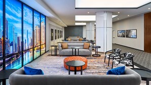 A modern lobby with a cityscape view, comfortable seating, and a central round ottoman. - Hotel Chicago Downtown, Autograph Collection by Marriott (Chicago)