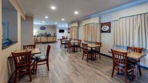 A dining area with wooden tables and chairs, a kitchen in the background, and a sign indicating a breakfast buffet. - Baymont by Wyndham Kirksville University Area (Kirksville)