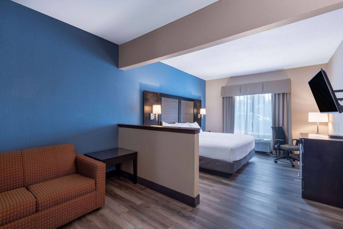 A hotel room with a bed, a desk, a chair, and a TV.