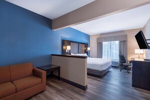 Habitación de hotel con cama, escritorio, silla y televisor.