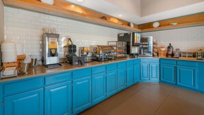 A kitchen with blue cabinets, a coffee machine, a toaster, and a refrigerator.