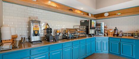 A kitchen with blue cabinets, a coffee machine, a toaster, and a refrigerator.