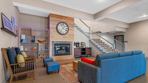 A modern living room with a fireplace, a staircase, and a blue sofa.