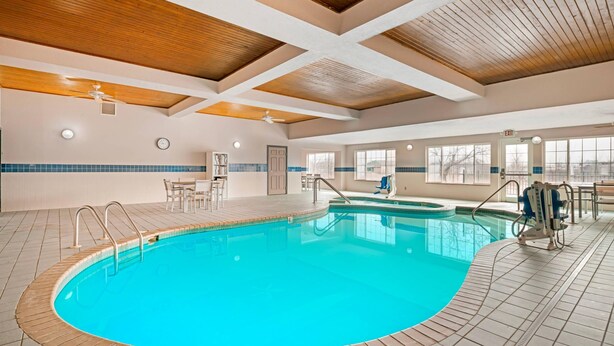 An indoor swimming pool with a wooden ceiling, tiled floor, and a wheelchair-accessible area.