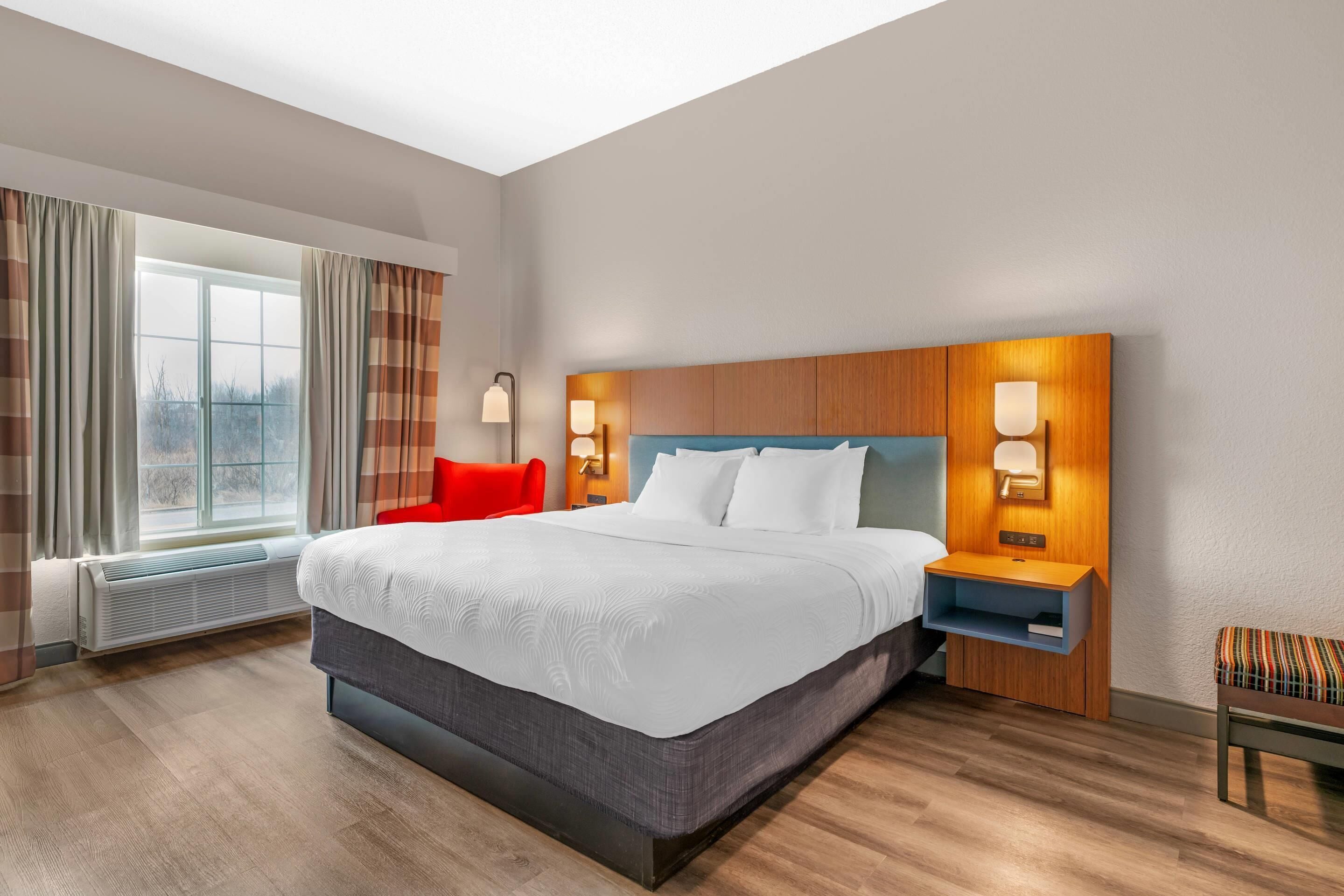 Une chambre d’hôtel avec un grand lit, des tables de chevet avec des lampes, une fenêtre avec des rideaux et une vue sur l’extérieur.
