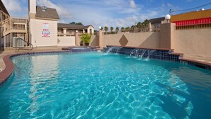 A clear blue pool with a tiled edge, a lifeguard tower, and a sign indicating pool rules. - SureStay Hotel by Best Western Deer Park (Deer Park)