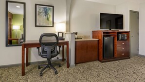 A hotel room with a desk, chair, TV, microwave, and refrigerator. - SureStay Hotel by Best Western Deer Park (Deer Park)
