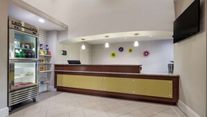 A reception area with a counter, a refrigerator stocked with beverages, and a television mounted on the wall. - SureStay Hotel by Best Western Deer Park (Deer Park)