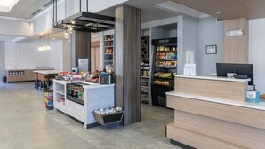 Um hall de hotel moderno, com balcão de recepção, área de estar e um espaço para alimentação.