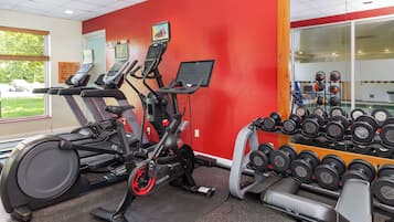 A gym with treadmills, an elliptical, and a rack of dumbbells.