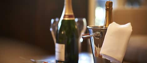 Una mesa con una botella de champán, una copa y un plato de aperitivos.