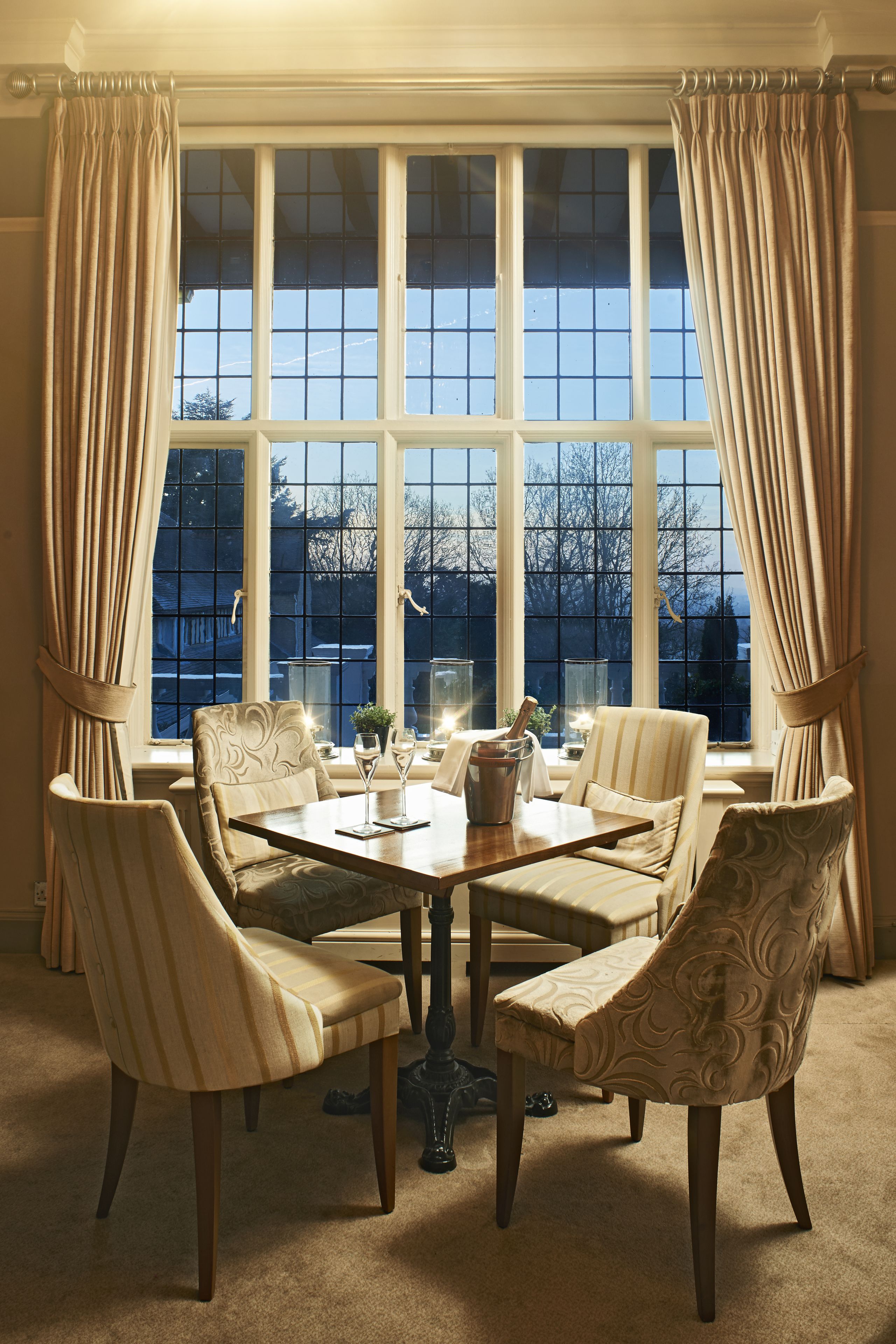 A dining room with a large window, a table set for four, and four chairs.