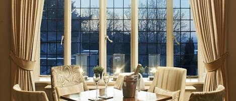 A dining room with a large window, a table set for four, and four chairs.