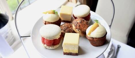 Un plato blanco con diversos postres sobre un soporte.