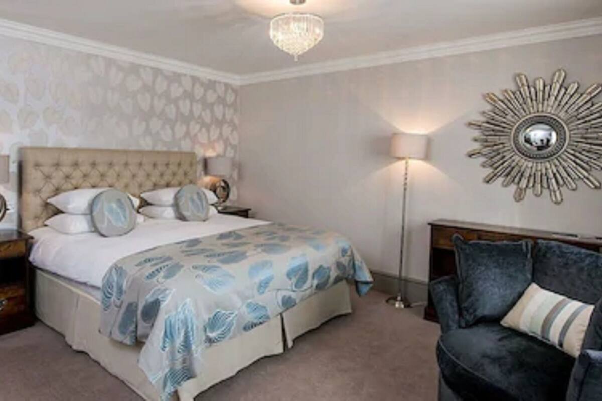 A bedroom with a bed, bedside tables, a lamp, a decorative wall piece, and a sofa.