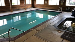 An indoor swimming pool with wooden walls, a tiled floor, and a lifeguard sign. - Super 8 by Wyndham LaGrande (La Grande)