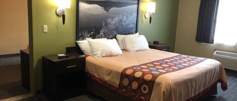 Habitación de hotel con una cama, dos mesitas de noche, una lámpara de pared, un reloj y una ventana con cortinas.