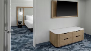 Une chambre d’hôtel équipée d’un lit, d’une table de chevet et d’un téléviseur fixé au mur.