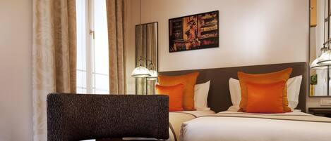 A hotel room with a bed, a chair, a lamp, and a painting on the wall.