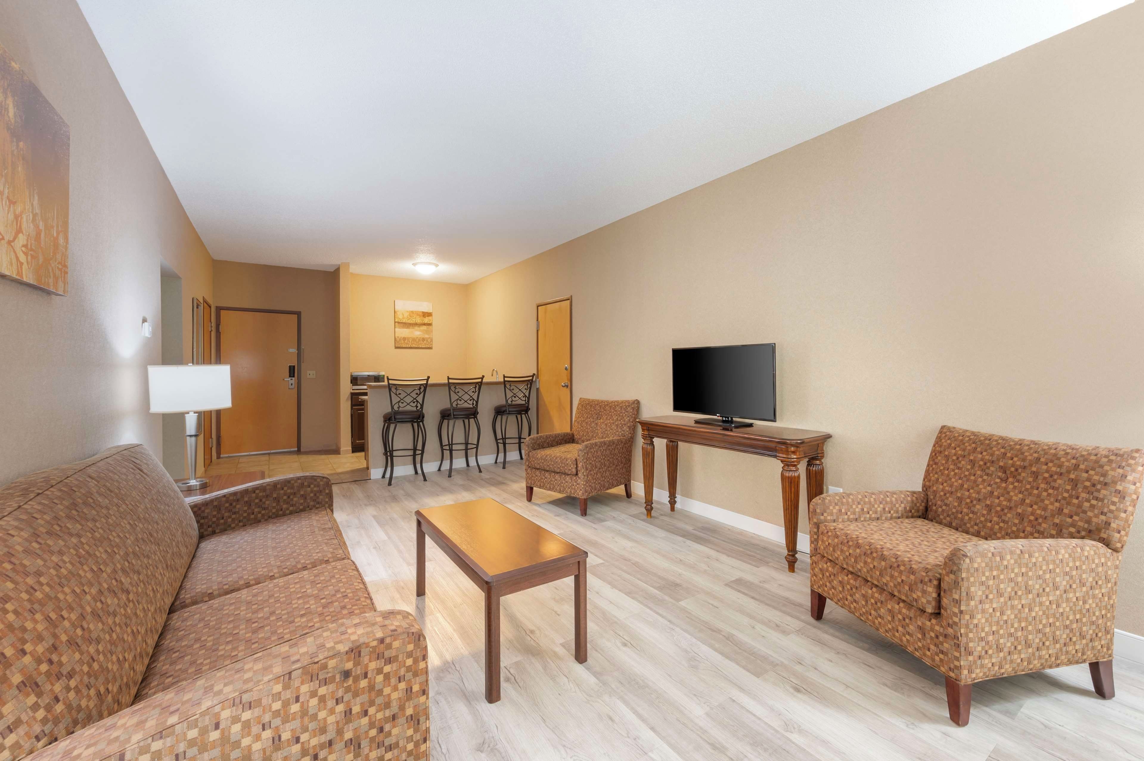 A living room with a sofa, armchairs, a coffee table, a TV, and a dining area with chairs and a table.