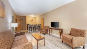 A living room with a sofa, armchairs, a coffee table, a TV, and a dining area with chairs and a table.
