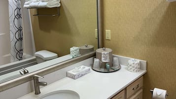A hotel bathroom with a sink, mirror, towel rack, toilet, and a mirror reflecting the room.