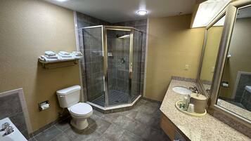 Un baño con ducha, inodoro, lavamanos y un perchero para toallas.