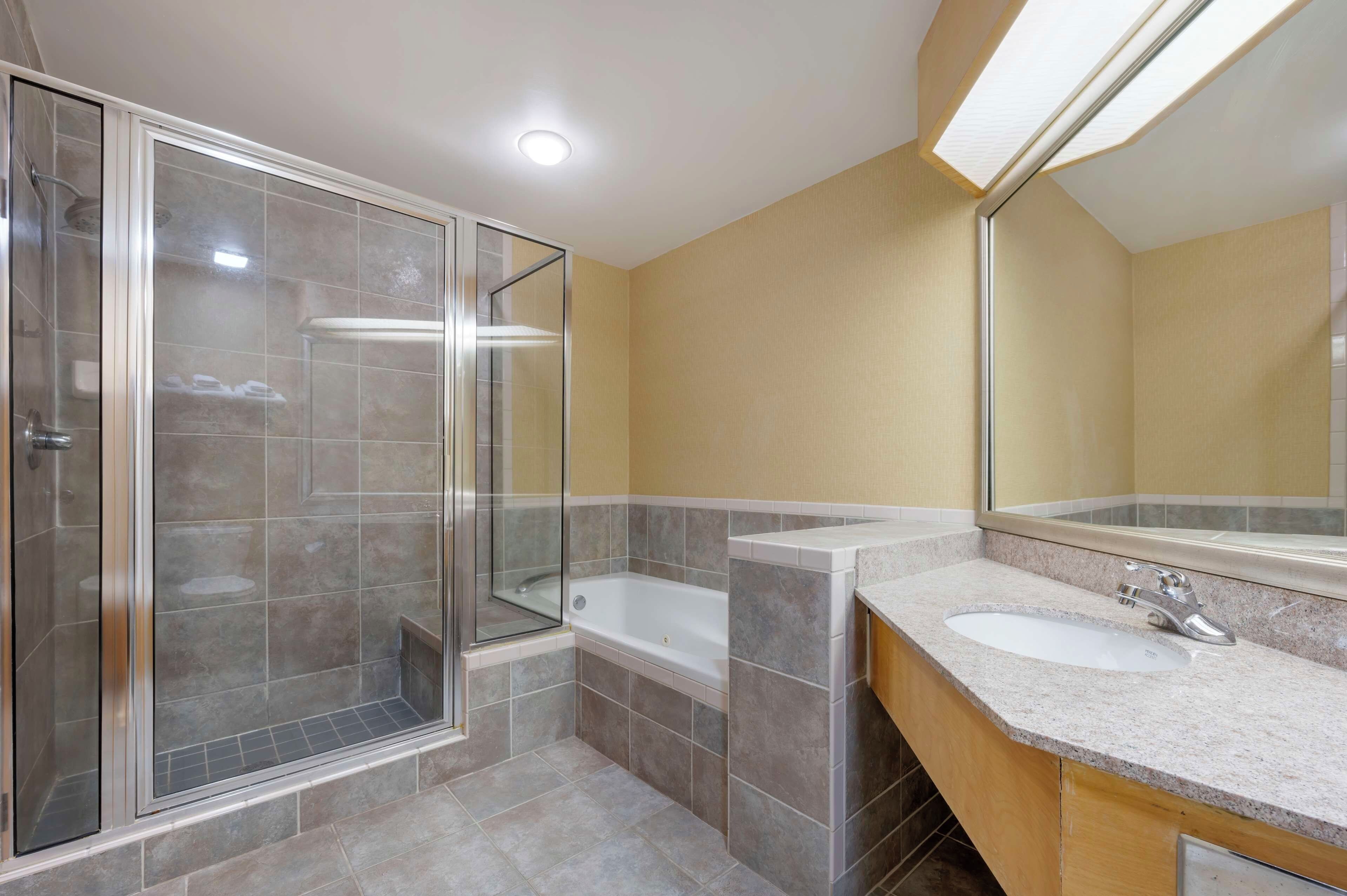 Une salle de bain moderne dotée d’une douche à parois de verre, d’une baignoire sur pieds et d’un meuble-lavabo.