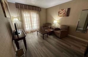 A hotel room with a wooden floor, two armchairs, a sofa, a small table, a TV, and a lamp. - Best Western Circus City Inn (Peru)