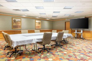 A conference room with a long table, four chairs, a projector screen, and a carpeted floor. - Best Western Circus City Inn (Peru)